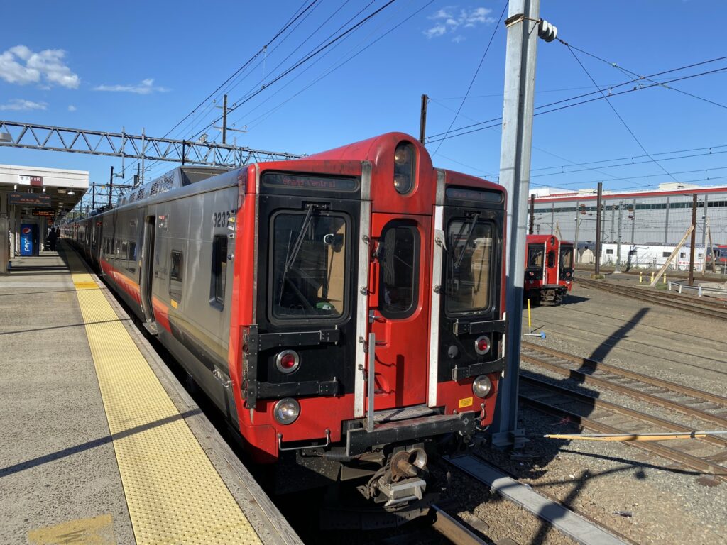 Kawasaki built M8 electric railcar in red and silver pulling up to the boarding station.