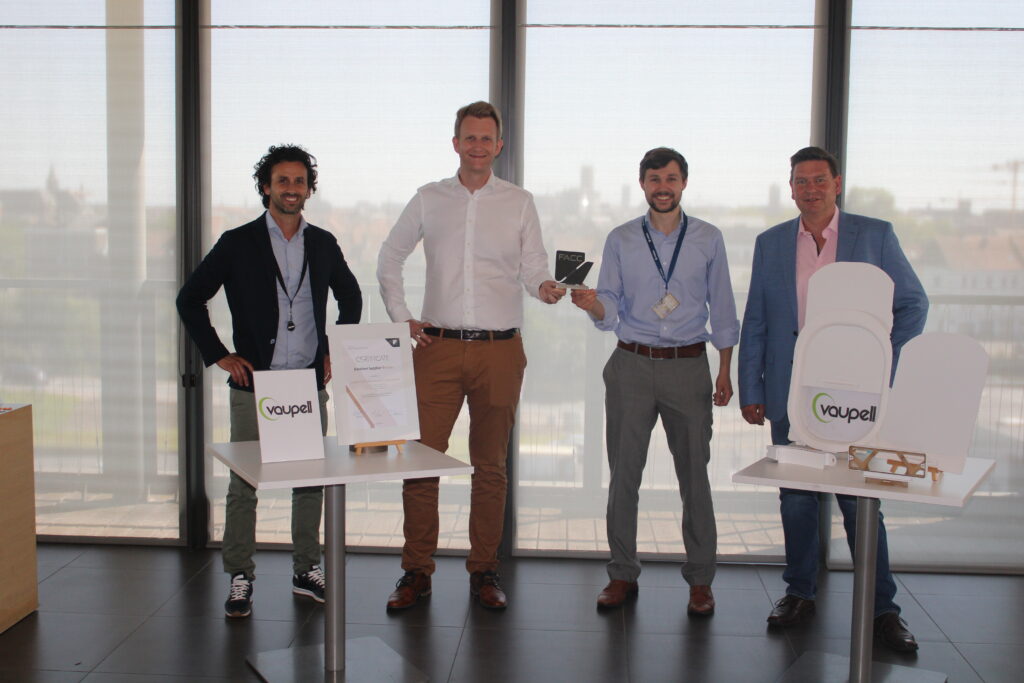 Vaupell team of 4 memebers posing for the photo with the awards received in front of a large window.