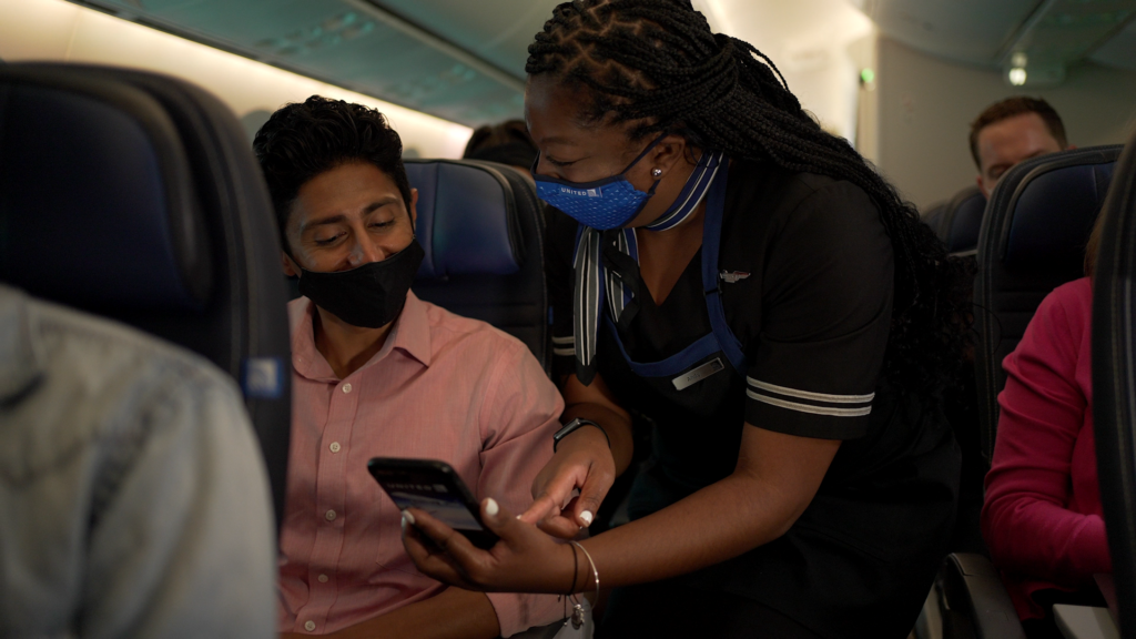 United flight attendant showing a passenger how to use pre-order for snacks.