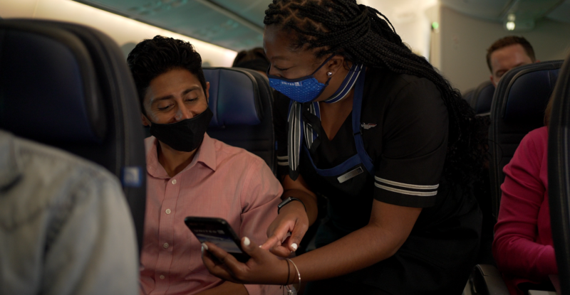 United flight attendant showing a passenger how to use pre-order for snacks. Cares