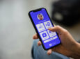 Hand holding a mobile device showing the IATA travel pass app.