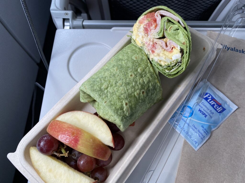 The egg and ham sandwich wrap is pictured on the tray table, with a Purell wipe sitting beside it