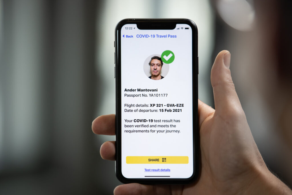 Hand holding a mobile device showing the IATA travel pass app.