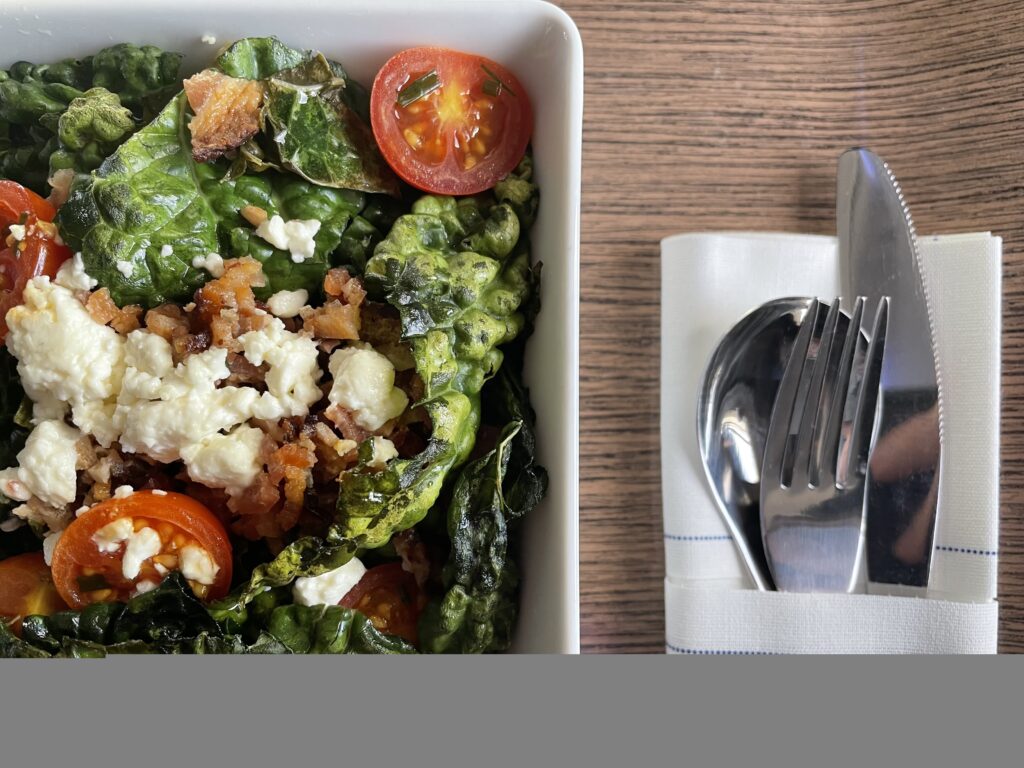 A beautifully dressed salad accompanied with silverware 