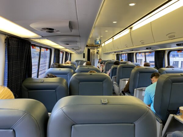 Interior of Acelra Amtrak train car. With grey seating. Some passengers are already seated.