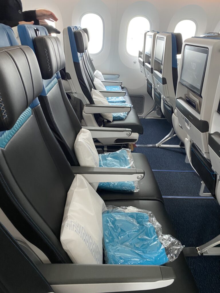 WestJet Boeing 787-9 economy class with blankets and pillows on each seat.