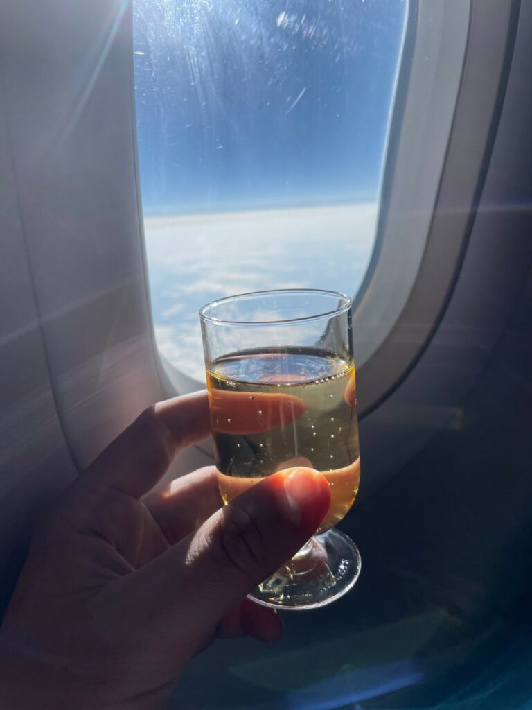 Hand holding a glass of champagne in front of an aircraft window on British Airways.