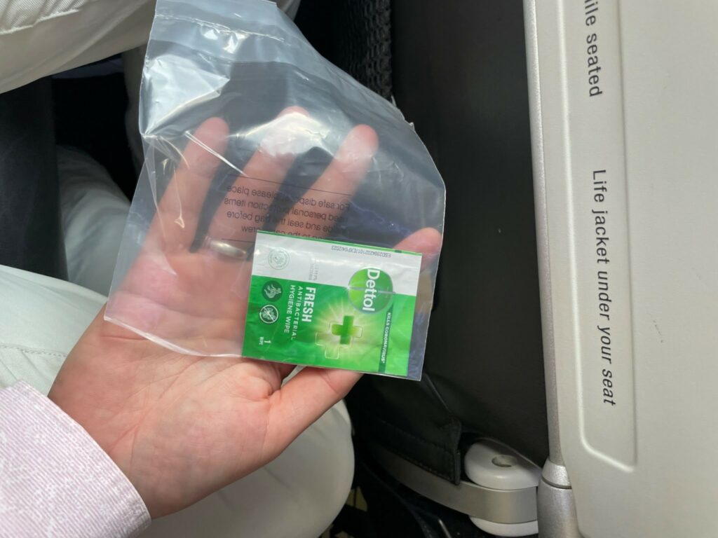 A passenger holding a single alcohol wipe to clean their seat on British Airways.