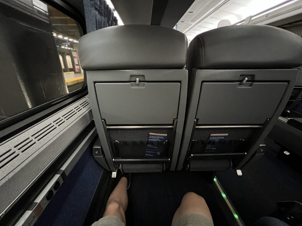 A man's knees showing plenty of space in the Amtrak Business Class seat.