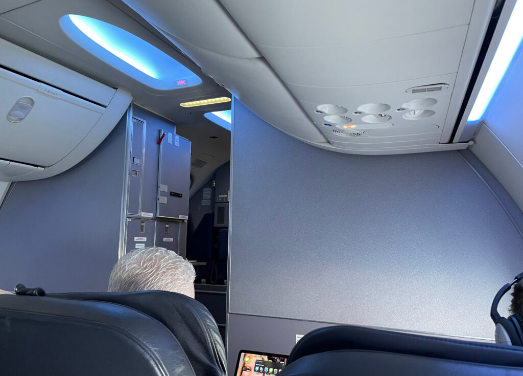 Overhead bins, blue LED lighting and two front row seats are in view