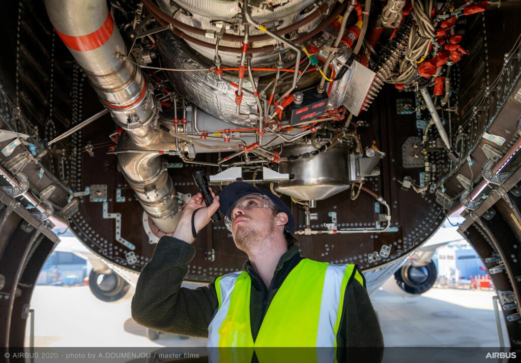 Technician looking under the belly of an aircraft.