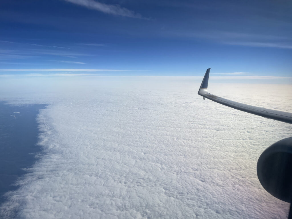 View out the window of a United flight, soaring above the clouds