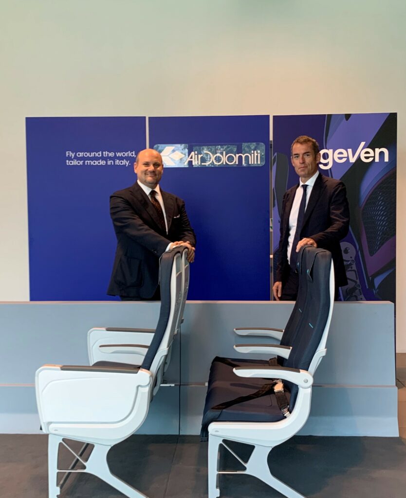 Execs from Air Dolomiti and Geven stand behind The Geven ESSENZA seat model on display.