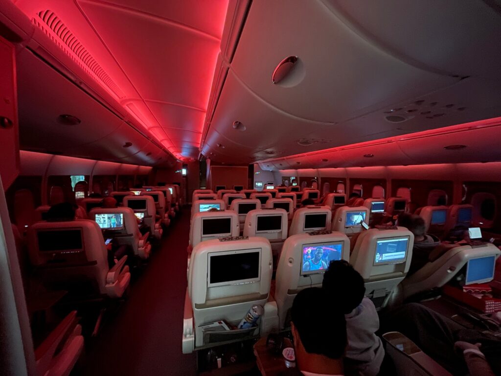 Emirates A380 cabin in economy class with red LED lighting and seatback IFE in view