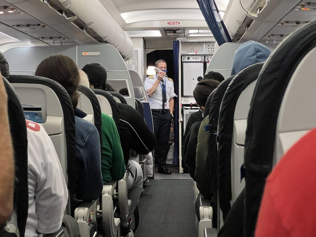 United Airlines A319 cabin interior full of passengers, with the captain providing a warm welcome