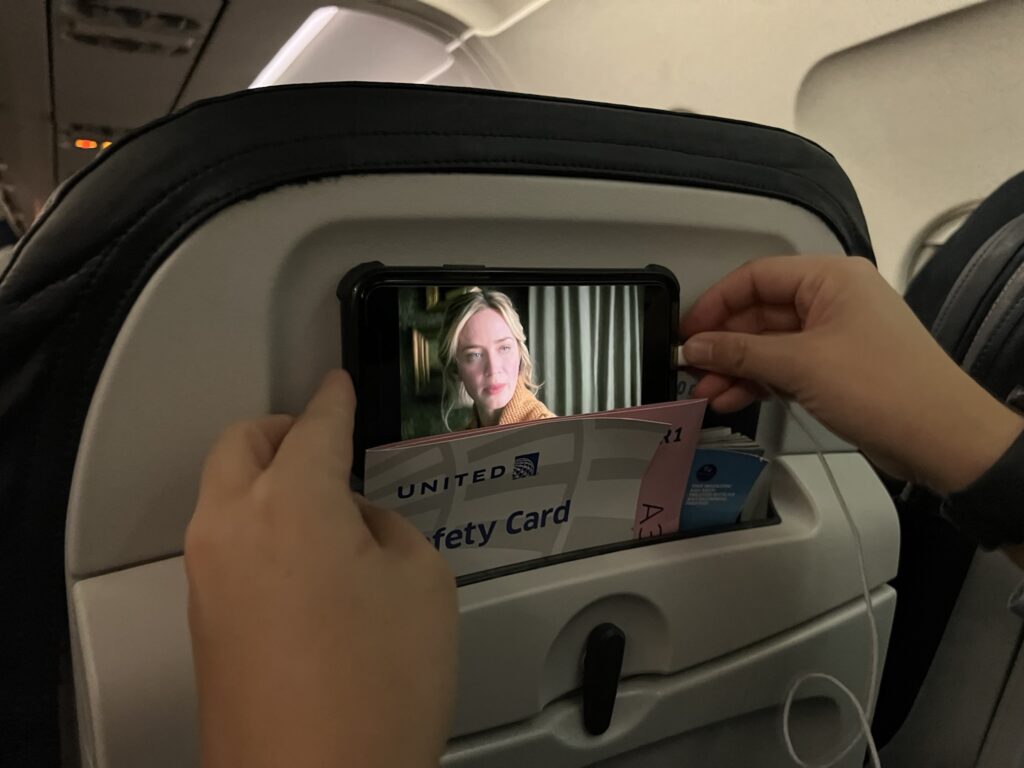 UA A319 passenger trying to position a smart phone for viewing in the literature pocket