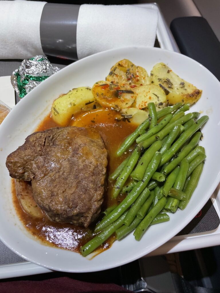 Meal of beef, beans and potatoes with gravy. The beef looks dry.