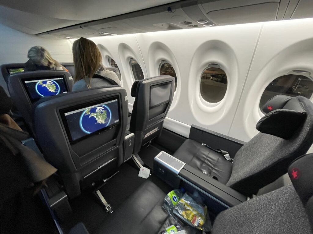 Air Canada A220-300 cabin interior. A moving map can be seen on the IFE screens