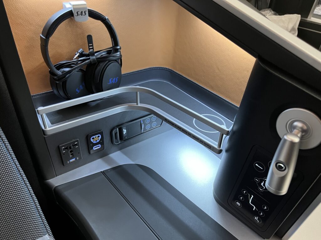 Power ports, a headset and storage area in the business class seat