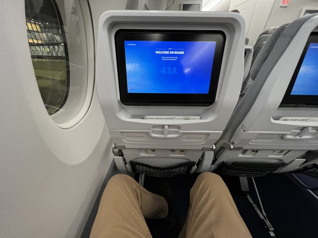 The author's legs are in view as he is seated onboard the Finnair A350