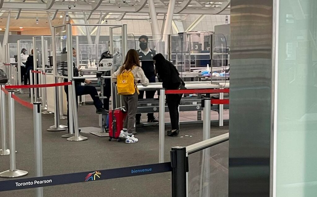 Young girl going through Toronto Pearson security with an Air Canada employee.