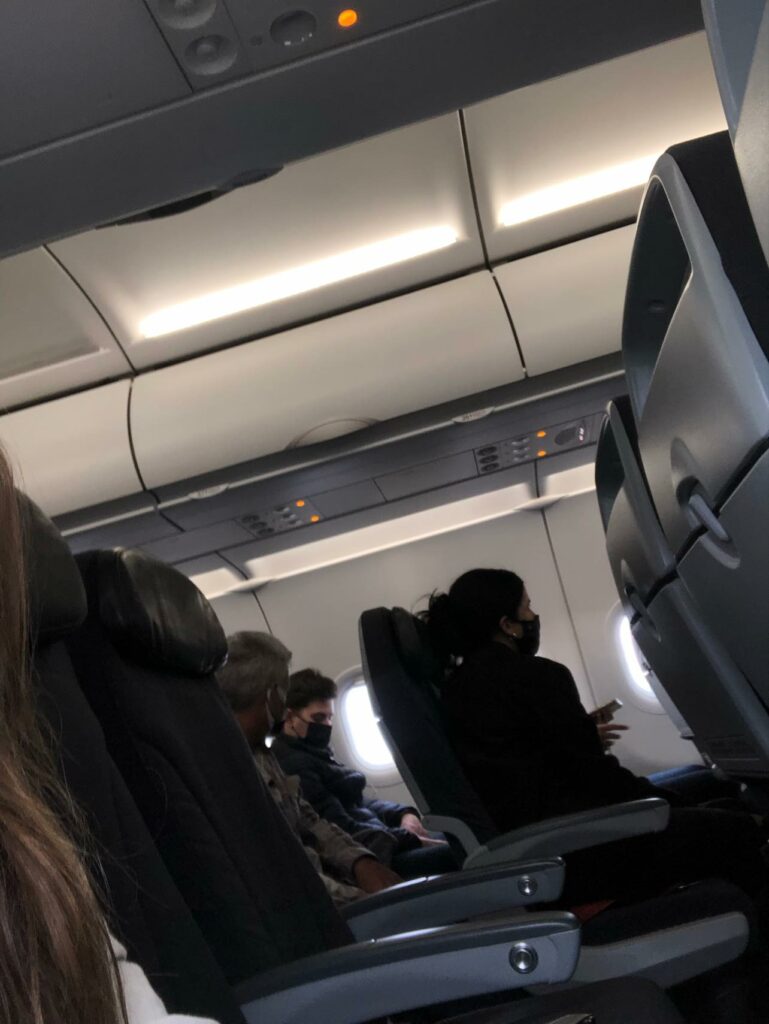 Air Canada Rouge Airbus A320 aircraft interior with masked passengers seated.