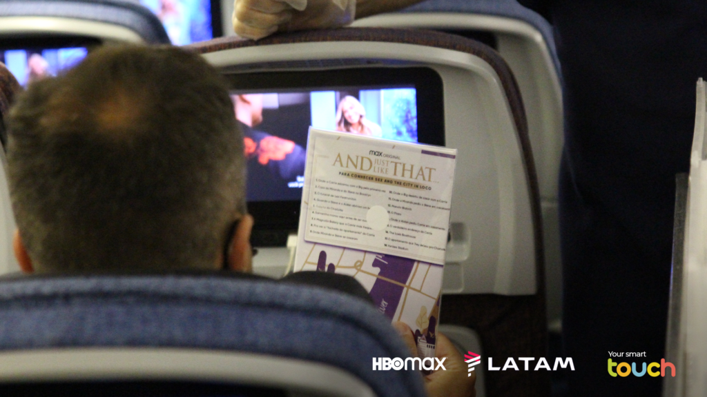 The back of a LATAM passengers head as he watches the newest episode of Sex and The City on the seatback IFE.