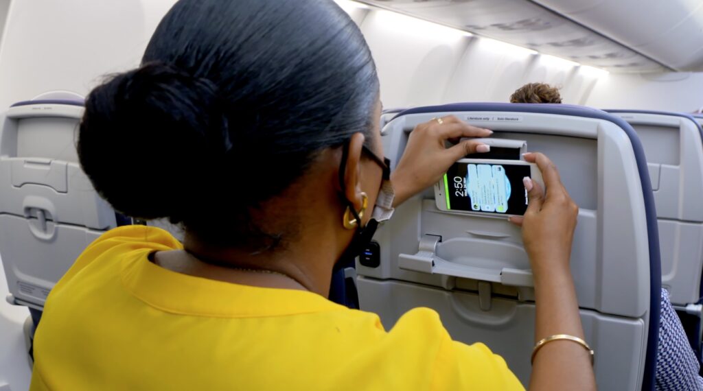 Female passenger placing her device in the PED holder of Caribbean Airlines Economy Class Seat