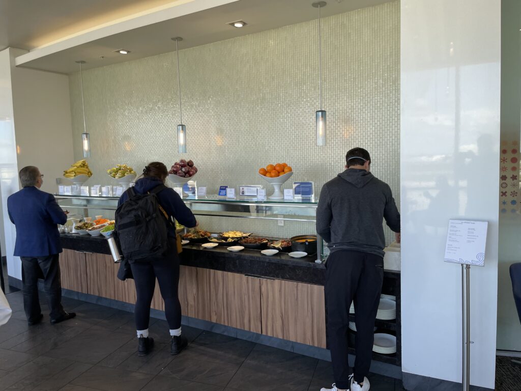 People are taking items from the lounges buffet. 