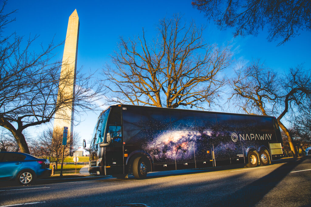 The Napaway coach buss is seen driving down a city street in the early spring.