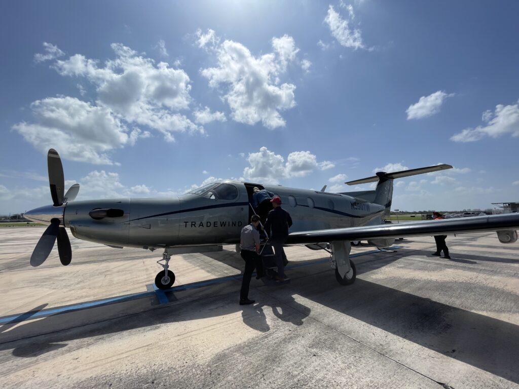 Passengers boarding the Tradewind Pilatus PC-12 on a bright sunny day.