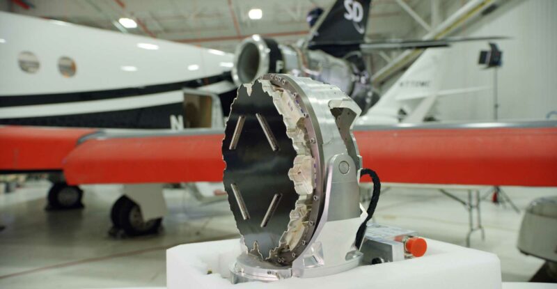 The Plane Simple Ku-band tail mount antenna sits on a table in this photo. A SD aircraft is seen blurred in the background.