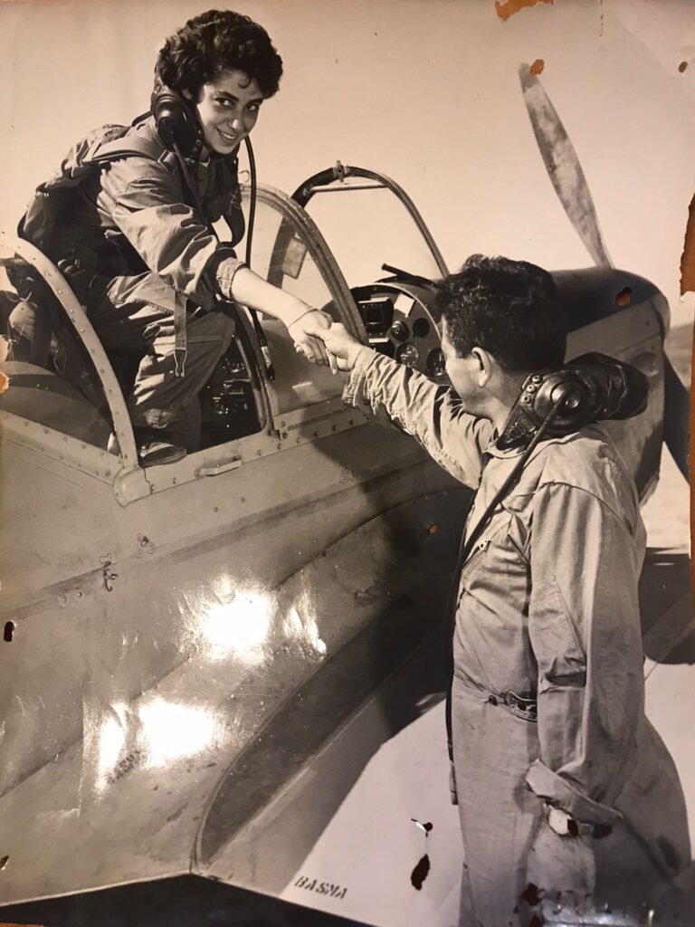 Senay Günay in her aircraft reaching out to shake hands with a man.