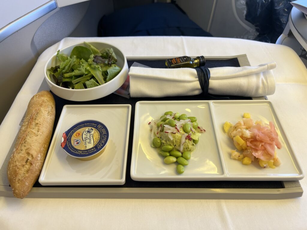 Various food options sit on rectangular plates atop an aircraft tray table.