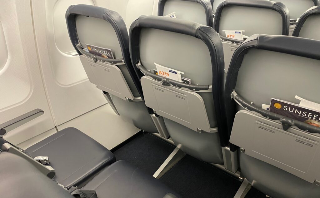 Allegiant A319 cabin interior shows gray seatbacks on skinny seats with blue covers