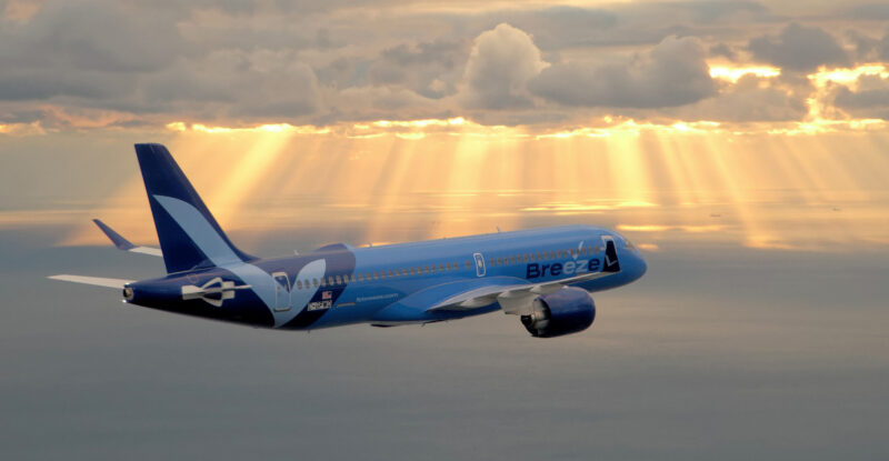 Breeze Aircraft flying above the clouds. Soft light rays shine through clouds above the aircraft and cascade down.