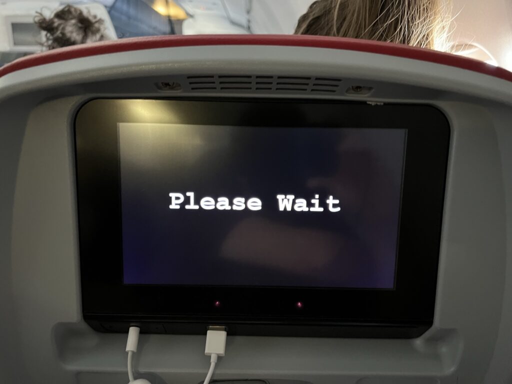 "Please wait" is displayed on the embedded IFE screen. 