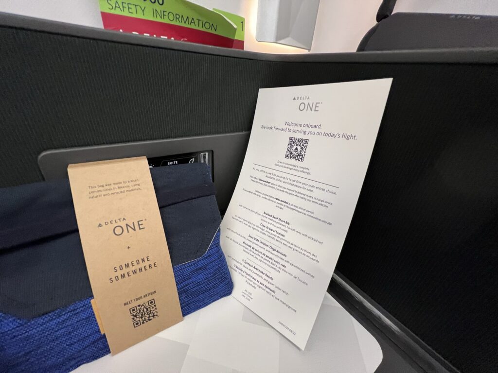 Both the Delta One menu and amenity kit are displayed on the side table of the suite. 