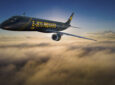 Embraer E195F inflight over the clouds. The aircraft is blue and has yellow lettering saying E-Jets Freight.