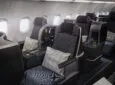 SAS Thompson Vantage seat is pictured here in various grey tones. Headphones ang to the side of the seat and a white a grey plaid pillow sits on top of the seat.