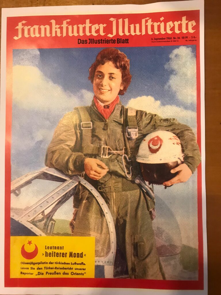 Senay Günay is pictured here on the front of a magazine. She is again standing in an aircraft holding her helmet.