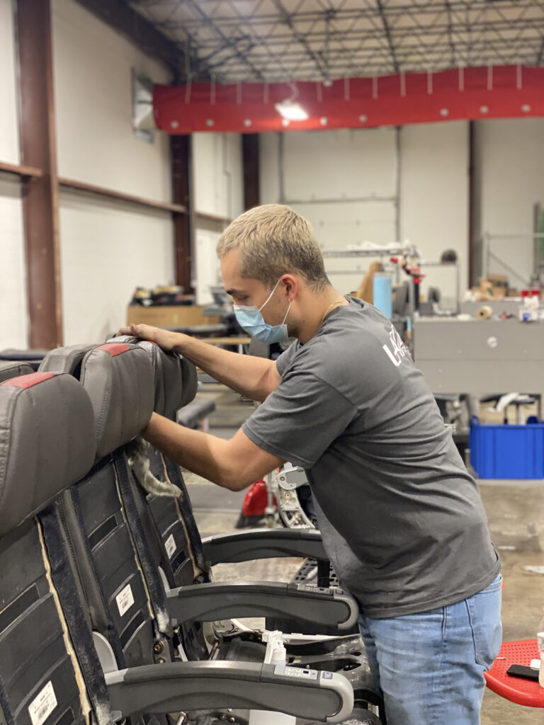 A man wearing a mask is working on aircraft seats in Latitude Aero's factory.