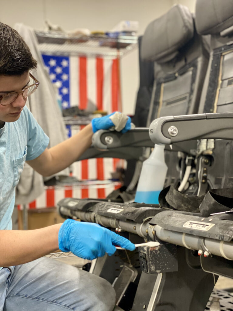 A young technician cleans a seat at Latitude Aero's facility.