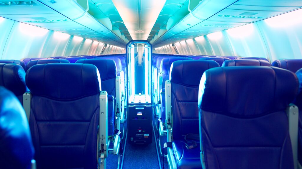 Aero HygenX Ray UV cleaner is seen here moving up Avelo Airlines' aircraft aisle powered on with its bright blue light.