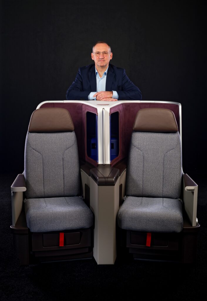 Thierry Kanengieser, VP  Cabin Interior STELIA Aerospace stands behind a display model of two Stelia Equinox seats.