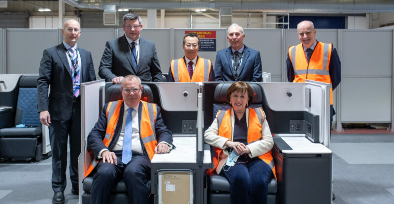 Thompson Areo Seating team members pose for a photo. Two are seated in TAS seats while the remainder stand in the behind the seats. Front row: Conor Burns MP; Diane Dodds MLA Northern Ireland Back row: David McCabe, Head of Transformation, Thompson; Neil Taggart, Vice President & General Manager, Thompson; Zhen Pang, CEO, AVIC Cabin Systems; Gordon Cracknell, Head of Operations, Thompson; Leslie Orr, Director of ADS Northern Ireland