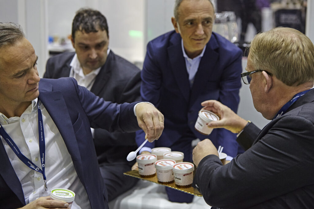 A man in a suit is handing out samples of a product to other menu.