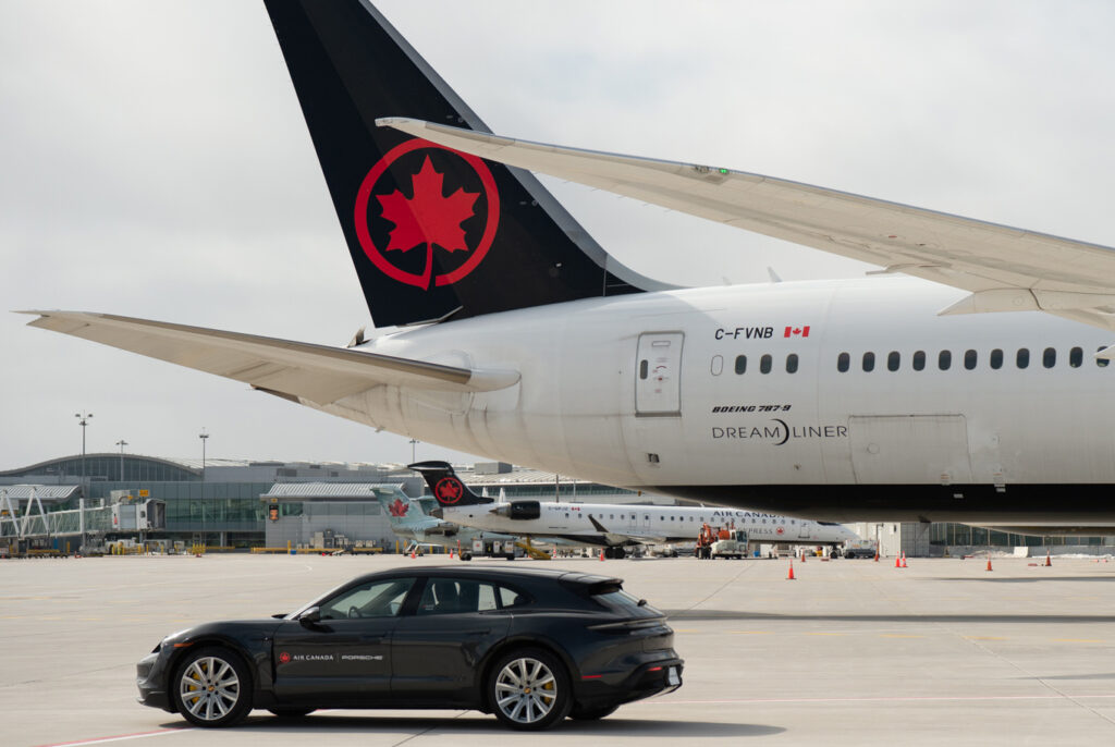 A Porsche is parked next to an Air Canada aircraft