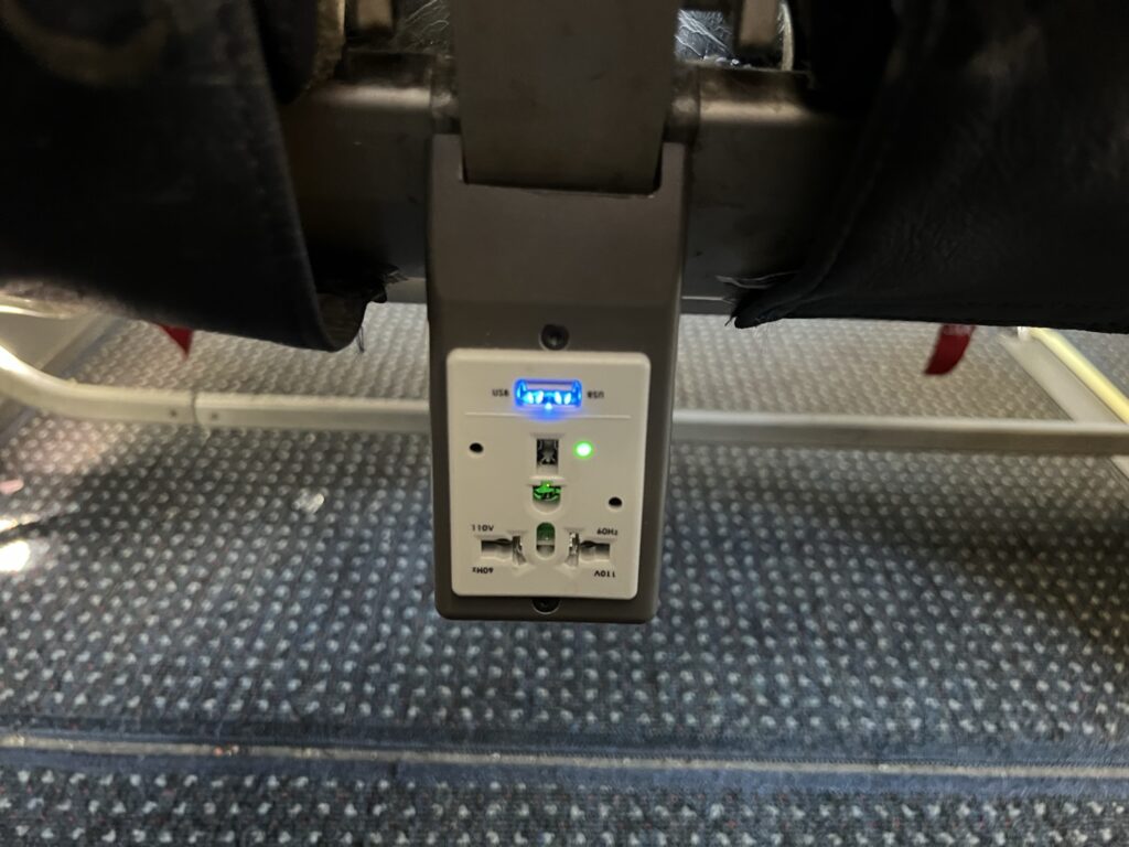 A close-up image of the an in-seat power outlet for passengers on American Airlines