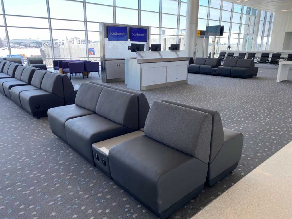 Southwest terminal at DEN shows various couch-like seating and the gate counter. Windows from floor to ceiling. 